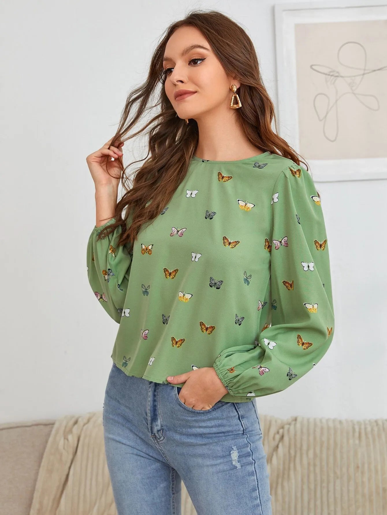 Green women's long-sleeved shirt with butterfly print, showing loose fit and long sleeves.