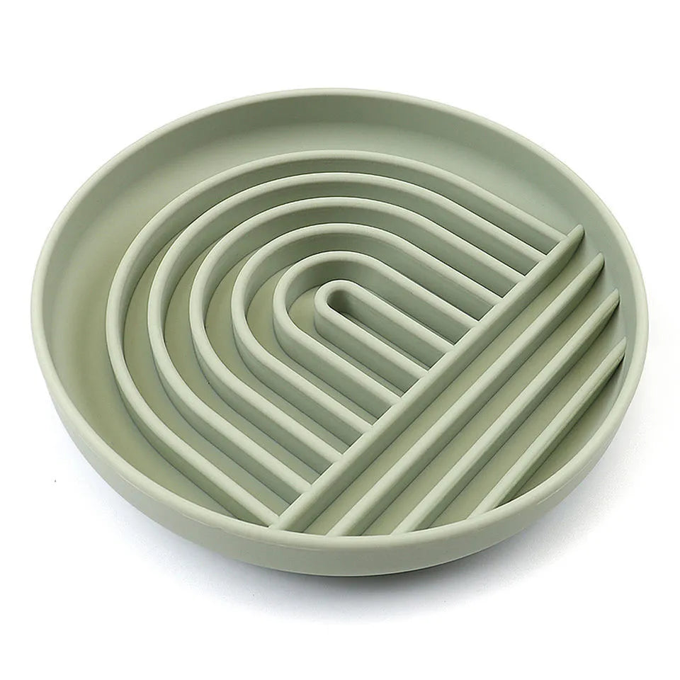 Beige silicone dog slow feeder bowl with ridges, shown next to a grey blue version on a wooden floor.