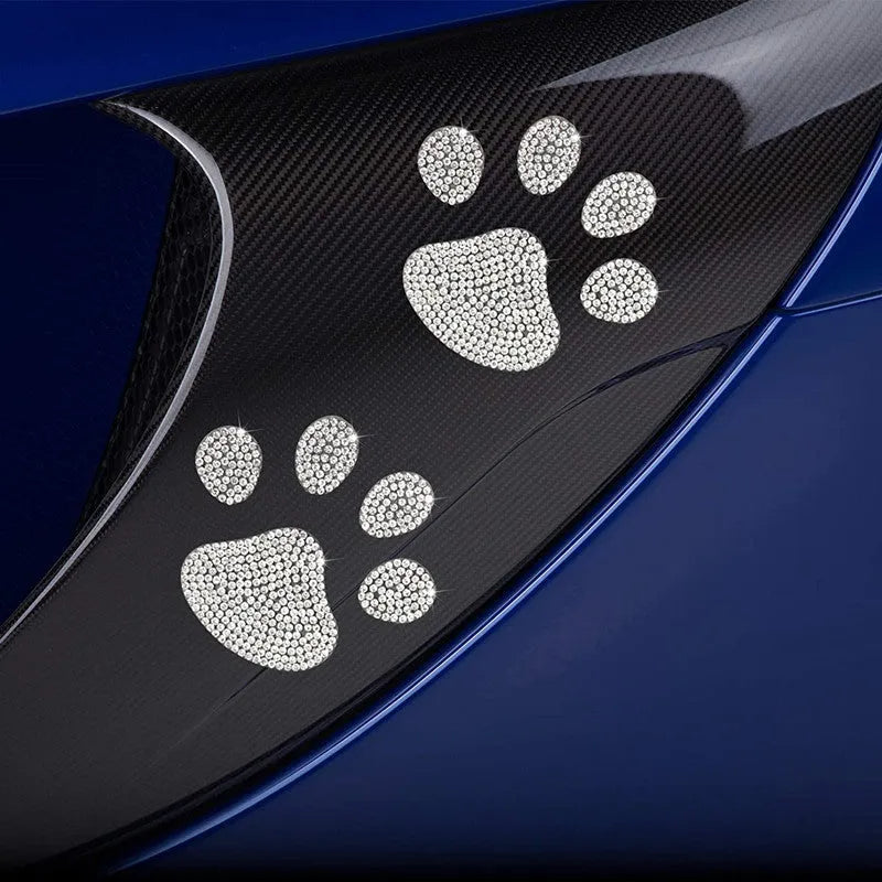 Close-up of a diamond-encrusted glass car sticker in a bear paw design on a car window.