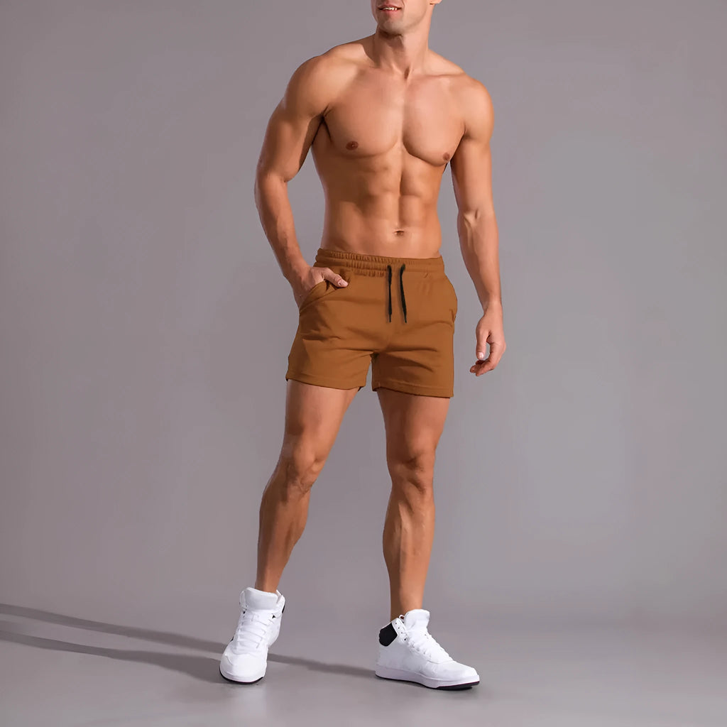 Pack of three men's solid colour drawstring shorts in black, khaki, and light brown on a hanger.