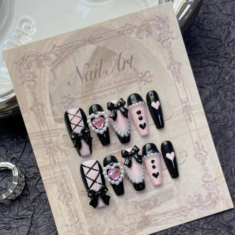 Black pink heart-shaped false nails with hand-painted bow design, Cat's Eye style, in mid-length profile.